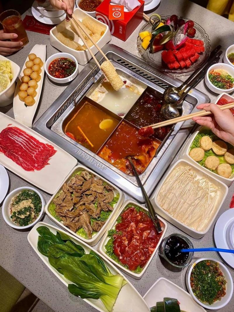 Một nhóm bạn đang vui vẻ lựa chọn món từ menu tại một quán ăn hải sản, thể hiện sự thảo luận khi gọi món